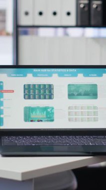 Borsa verileri ve istatistikleri gösteren dizüstü bilgisayar ve tabletin yer aldığı dikey video Finans analisti. Masadaki cihazların yakın plan görüntüsü ön ödeme ekonomisi olan kağıt işlerinin yanında.