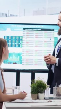 Dikey video finans danışmanı, geniş ekran kullanarak müşterilere piyasa analizlerini sunuyor, portföy inşa etmek için en iyi uygulamaları keşfediyor. Borsa komisyoncusu anneme borsa çizelgeleri gösteriyor.
