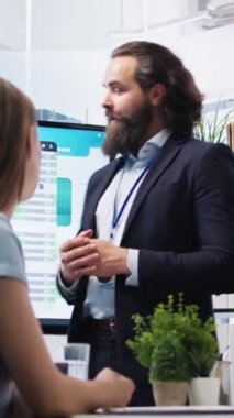 Dikey video finans danışmanı, geniş ekran kullanarak müşterilere piyasa analizlerini sunuyor, portföy inşa etmek için en iyi uygulamaları keşfediyor. Borsa komisyoncusu anneme borsa çizelgeleri gösteriyor.