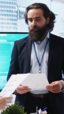 Büyük ekranda müşterilere istatistiksel grafikler gösteren dikey video finans danışmanı, piyasa eğilimlerini geliri optimize etmek için analiz ediyor. Sergilenen yatırım planını kontrol eden aile üyeleri
