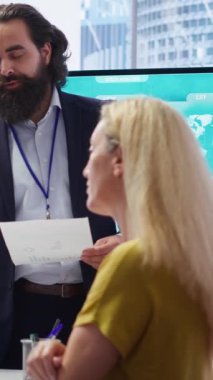 Büyük ekranda müşterilere istatistiksel grafikler gösteren dikey video finans danışmanı, piyasa eğilimlerini geliri optimize etmek için analiz ediyor. Sergilenen yatırım planını kontrol eden aile üyeleri