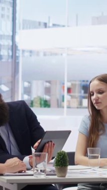 Finansal stratejileri sunan ve tablet kullanan müşterilere rehberlik eden dikey video danışmanı. Ofisteki ajan, anne ve kızına yatırım portföyü yönetimi için yardım ediyor.