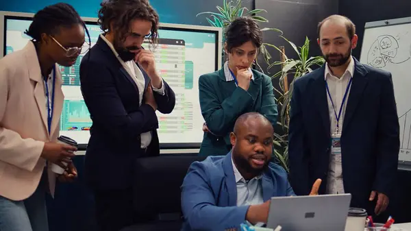 stock image Diverse corporate employees analyzing project updates to ensure goal accomplishment, reviewing infographics on laptop and finding ways to obtain new funds. Business management team. Camera B.