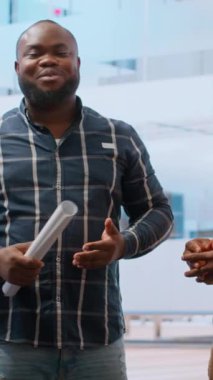 Dikey Video Emlak komisyoncusu ve müşterisi ofis alanının planlarını analiz ediyor, mülkü değerlendiriyor ve bir sözleşme imzalıyor. İşadamı bir yatırım stratejisi planlıyor. Kamera B.