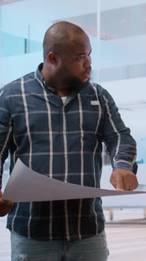 Dikey Video Emlakçısı ve müşterileri, modern yüksek sınıf binaların mimari tasarım ve planlarını değerlendirerek yeni ofis binasının ayrıntılı planlarını tartışıyor. Yatırım fırsatı