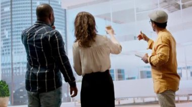 Şirket müşterileri ve bir emlakçı, yeni ofis mülkünün mimari planları, tasarımı ve yatırım potansiyeline odaklanarak kira sözleşmesi üzerinde görüşüyorlar. Pazarlık peşindeyim. Kamera A.