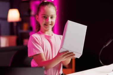 Çocuk içerikli yaratıcının portresi yüksek kaliteli kayıt cihazları kullanarak çevrimiçi platformlarda yayın yapan kanal için boks olmayan ürünler çekiyor. Çocuk hayranlarını sıcak bir şekilde karşılıyor, elektronik eşyaları yerleştiriyor.