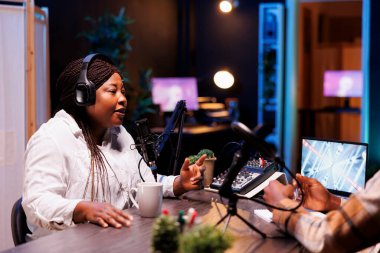 Afrika kökenli Amerikalı kadın etkili radyo sunucusu sorularını cevaplarken stüdyosundaki bir mikrofona konuşuyor. Kablosuz kulaklık takan genç siyahi bayan internet sohbet programı yapıyor..