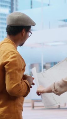 Vertical Video Business profesyonel ve emlak komisyoncusu, yüksek sınıf ofis kiralama sözleşmesi için dizüstü bilgisayardaki planları gözden geçirip mimari tasarım ve yerleşim planlarını tartışıyorlar. Almayı planlıyorum.