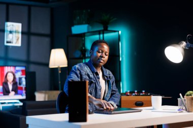 Afrikalı Amerikalı serbest çalışan kadın kişisel bilgisayarını açıyor, ofis masasında çalışmaya hazırlanıyor. Çevrimiçi araştırma için dijital dizüstü bilgisayar kullanan kararlı siyahi kadın.