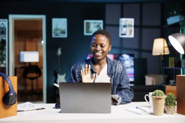 Heyecanlı siyahi kadının portresi kişisel bilgisayardaki bir konferans görüşmesinde merhaba jesti yapıyor. Afrikalı Amerikalı öğrenci bilgisayarla iş arkadaşlarıyla görüntülü konuşma yapıyor..