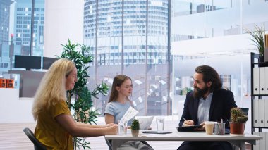 Mali danışman müşterilerle görüşüyor, uygun sigorta poliçeleri öneriyor. Ajan, en iyi yatırım stratejilerini ailesine ve kızına bildiriyor, istatistik sunuyor, kamera A