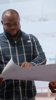 Bir ofis turundaki gayrimenkul potansiyelini değerlendiren dikey video işkadını, çalışma alanının taşınması için bir tabletin ayrıntılı planlarını inceliyor. Girişimci güvenilir olmayı planlıyor