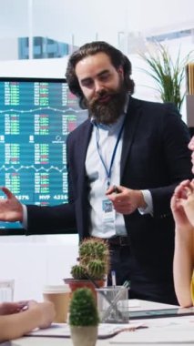 Ofisteki dikey video komisyoncusu müşterilerine finansal tavsiyelerde bulunuyor. Büyük ekrandaki borsa dalgalanmalarına bakıyor. Piyasa büyümesini anneyle analiz eden mali danışman ve