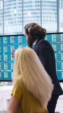 Daha fazla para kazanmak isteyen müşterilere hisse senedi değer analizi sağlayan dikey video komisyoncusu. Finansal danışman büyük ekrandaki pazar hisselerine bakıyor, insanlara yardım ediyor