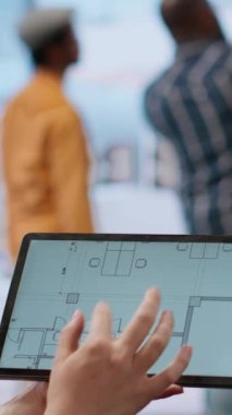 Dikey video emlakçı ve müşteri planlarını değerlendiriyor ve ofis turu sırasında yeni ofis alanının mimari planını tartışıyor. Şirketin yerini değiştirmeyi planlayan bir iş adamı.