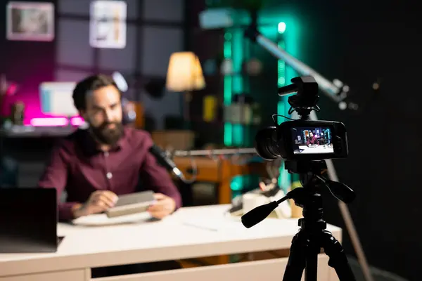 stock image Focus on tech guru in blurry background doing technology review of wireless portable speaker. Close up shot of professional camera used by influencer to record music playing device review