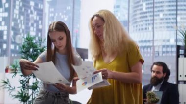 Müşteriler pazar eğilimlerini analiz eden mali danışman tarafından verilen istatistiksel tablolara bakıyorlar ve gelirlerini optimize etmek için bilgilendirilmiş tavsiyelerde bulunuyorlar. Yatırım planı okuyan kadınlar, kamera B