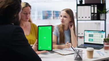 Elinde yeşil ekran tableti olan bir broker, borsa analizi yapmak için müşterilerle görüşüyor. Piyasa hisselerine bakan, ailenin gelirini en üst düzeye çıkarmasına yardım eden krom anahtar cihazlı mali danışman, kamera A