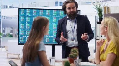 Büyük ekran kullanarak müşterilere yatırım stratejileri sunan mali danışman, borsa tahvilleri öneriyor. Ofisteki borsacı aileye ipo forex portföy yönetimi, kamera B