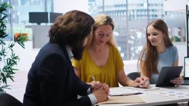 Finansal danışman müşterilerle mali danışmanlık toplantısı, gelecekteki yardımlar için sözleşme imzalama. Anne ve kızı kredi alabilmek için evrakları imzalıyorlar, kamera A.