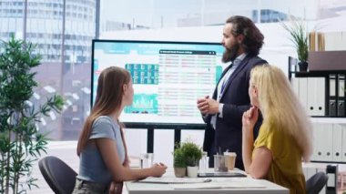 Finansal danışman, geniş ekran kullanarak müşterilere piyasa analizlerini sunuyor, portföy inşa etmek için en iyi uygulamaları keşfediyor. Broker ajanı anne ve kızına borsa çizelgeleri gösteriyor, kamera B