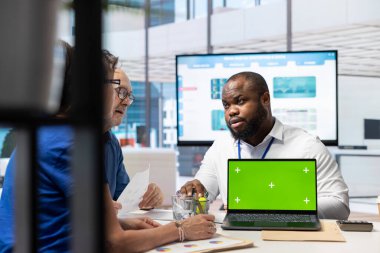 Orta yaşlı müşteriler bir bankacı danışmanından danışmanlık istiyor, emeklilik planı yoluyla emekli aylığını güvence altına almak için finansal seçenekleri araştırıyorlar. Komisyoncu yeşil ekran ekranlı bir dizüstü bilgisayar kullanıyor, tasarruf artışı.