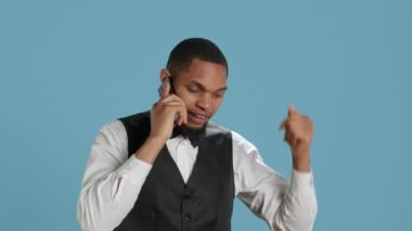 Smokinli otel hademesi stüdyoda telefonla rezervasyon yaptırıyor, gelecekteki misafirlerle konaklama ve konforu tartışıyor. Kapıcı otel görevlisi telefon hattında. Kamera A.