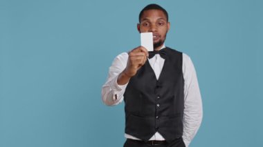 Otel kapıcısı giriş yaptıktan sonra oda giriş kartını sunuyor, beş yıldızlı tatil beldesinde lüks konaklama ve konfor sağlıyor. Resepsiyon personeli misafirlere yardım eder. Kamera B.