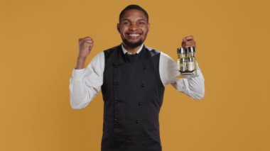 Mutlu garson sarı arka plana karşı tezahürat yapıyor, kendinden emin ve memnun. Çalışan, profesyonel hizmet görevinden duyduğu memnuniyeti dile getiriyor. Kamera B.