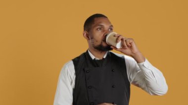 Restoran garsonu iş molasında bir fincan kahve içiyor, görevdeyken kafein içeceği ile rahatlıyor. Çalışan müşteri hizmetleri konukseverlik endüstrisinde çalışıyor. Profesyonellik. Kamera A.