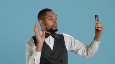 Klas otel hademesi akıllı telefondan video çağrısına cevap veriyor, müşterilerle ya da arkadaşlarıyla mavi arka planda tartışıyor. Çevrimiçi video konferans bağlantısında kapıcı. Kamera A.