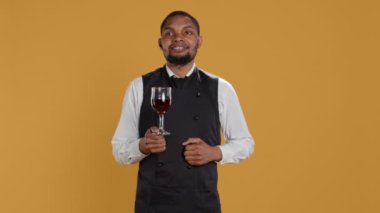 Garson, masada yemeklerini bekleyen müşterilere bir bardak şarap ikram ediyor. Restoranda mükemmel hizmet veriyor. Üniformalı profesyonel personel müşterilere içki getiriyor. Kamera B.