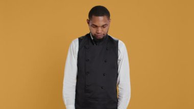 Profesyonel sunucunun portresi. Stüdyoda kolları kavuşturulmuş şekilde duruyor. Beş yıldızlı restoran üniformasını giyiyor ve müşterilerine hizmet ediyor. Müşteri odaklı garson. Kamera B.