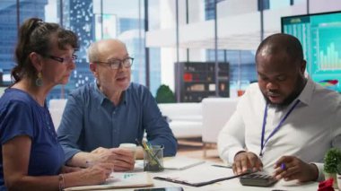 Emeklilik seçeneklerini araştırmak için bir komisyoncuya danışan yaşlı vatandaşlar, tasarruf ve yatırımlarının gelecek için optimize edilmesini sağlıyorlar. Emeklilik birikimleri hakkında finans uzmanıyla görüşeceğim. Kamera B.