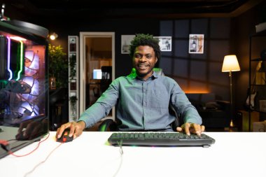 Neşeli oyuncu bilgisayar bilgisayarında oynarken sonunda tüm düşmanlarını yendikten sonra heyecanlanıyor. Gülümseyen Afrikalı Amerikalı adam bilgisayar oyunu kazandıktan sonra kendini tebrik ediyor.