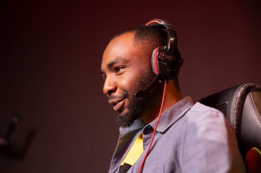 Kulaklıklı neşeli bir oyuncu oyun odasında eğleniyor, bilgisayarda video oyunları oynuyor. Mutlu esportçuların gece geç saatlerde evden oyun turnuvasında performanslarını yakından çek.