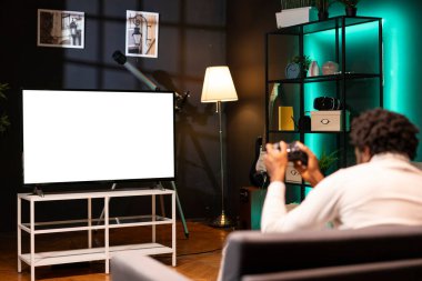 Evdeki oyuncu, denetçiyle oyun oynamak için TV setini kullanıyor. Oturma odasında kanepede oturan bir adam buhar çıkarmak için izole ekran akıllı TV 'de video oyunu oynuyor.