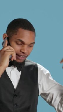 Smokinli Dikey Video Otel hademesi stüdyoda telefonla rezervasyon yaptırıyor ve gelecekteki misafirlerle konaklama ve konforu tartışıyor. Kapıcı otel görevlisi telefon hattında. Kamera A.