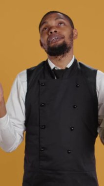 Stüdyoda Tanrı 'ya dua eden ve dine ve ruhaniliğe inandığını gösteren bir video servis elemanı. Dindar garson İsa 'ya sarı arka plan için dua ediyor. Kamera.