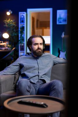 TV 'de yayınlanan iç karartıcı filmi izleyen adam sonunda ölen ana karakterden üzüntü duyuyor. Sinema sahnesindeki sorunlu olaylardan etkilenmiş üzgün gözleri olan biri.