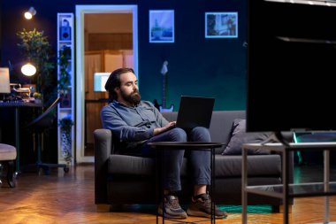 Apartman dairesinde televizyon izleyen ve bilgisayardaki işle ilgili görevleri çözen bir adam. Oturma odasındaki koltukta çalışan bir çalışan filmlere bakıyor ve not defteri üzerinde çalışıyor.