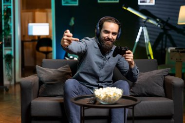 Orta parmak işaretleri gösteren neşeli bir adam tüm rakip oyuncuları yendikten sonra bilgisayar oyunu zaferini kutluyor. Oyuncu kaba el hareketleri yapıyor, oyunu kazandıktan sonra heyecanlanıyor, mutluluk duyguları sergiliyor.