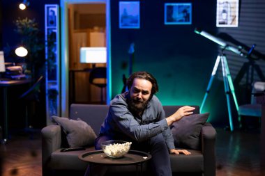 İşten izin günlerinde televizyon kanalında drama filmi izlerken ağlayan üzgün bir adam. TV 'de yayınlanan etkileyici film sahnesini izledikten sonra ağlayan kişi patlamış mısır yiyor.