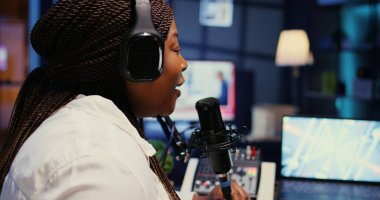 Canlı yayın kanalında yüksek teknolojili mikrofon kullanarak stüdyodaki nüfuzlu kişiyi yakınlaştır. Kadın, profesyonel yayın ses ekipmanıyla podcast seansı yapıyor, yakın çekim.
