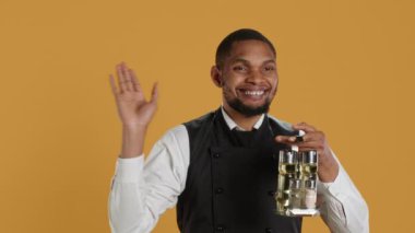 Mutlu garson el sallıyor ve müşterileri karşılıyor. Elinde müşterilere servis edilecek soslu bir şişe var. Lokantada insanları karşılayan neşeli, sevimli personel. Kamera A.