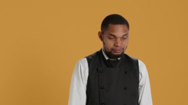 Profesyonel sunucunun portresi. Stüdyoda kolları kavuşturulmuş şekilde duruyor. Beş yıldızlı restoran üniformasını giyiyor ve müşterilerine hizmet ediyor. Müşteri odaklı garson. Kamera A.