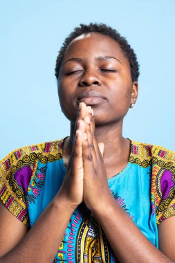 Tanrı 'yla konuşmak, şükran duası etmek ve stüdyoda İsa Mesih' le iletişim kurmak için dua eden kendine güvenen ciddi bir insan. Tanrı 'ya dua eden dindar bir kadın, Afro-Amerikan giysileri..