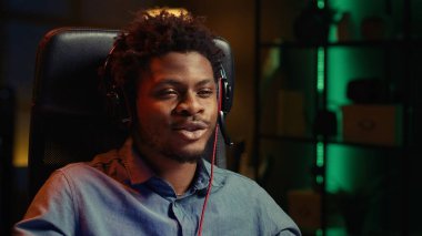 Video oyunu oynarken, masada otururken takım arkadaşlarıyla konuşmak için kulaklık takan Afrikalı Amerikalı bir adam. Oyuncu bilgisayar masaüstünde oyun oynarken çevrimiçi arkadaşlarla sohbet ediyor