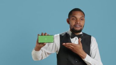 Otel görevlileri akıllı telefonda krom anahtar görüntüsü gösteriyorlar. Stüdyoda konukseverlik endüstrisi üniformasıyla poz veriyorlar. Kapıcı salonu personeli yeşil ekran gösteriyor. Kamera A.